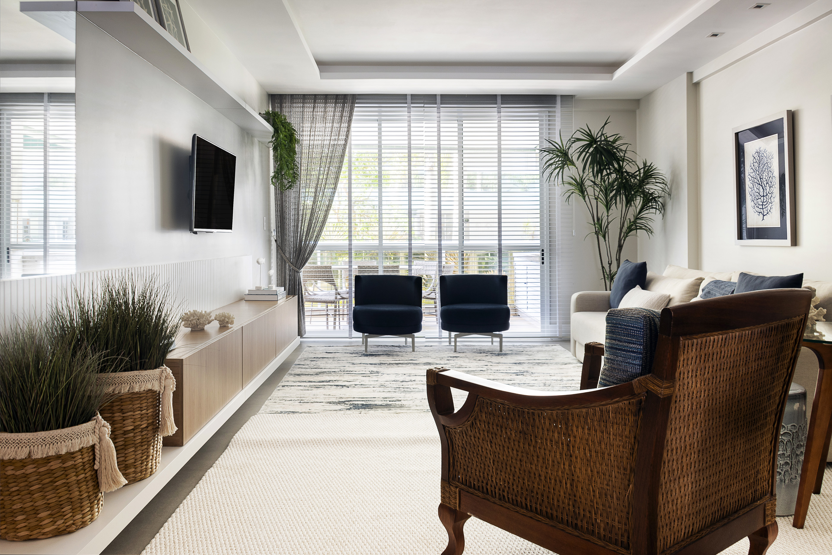 Sala de apartamento à beira-mar com poltronas azuis e fibras naturais, projeto Maresia