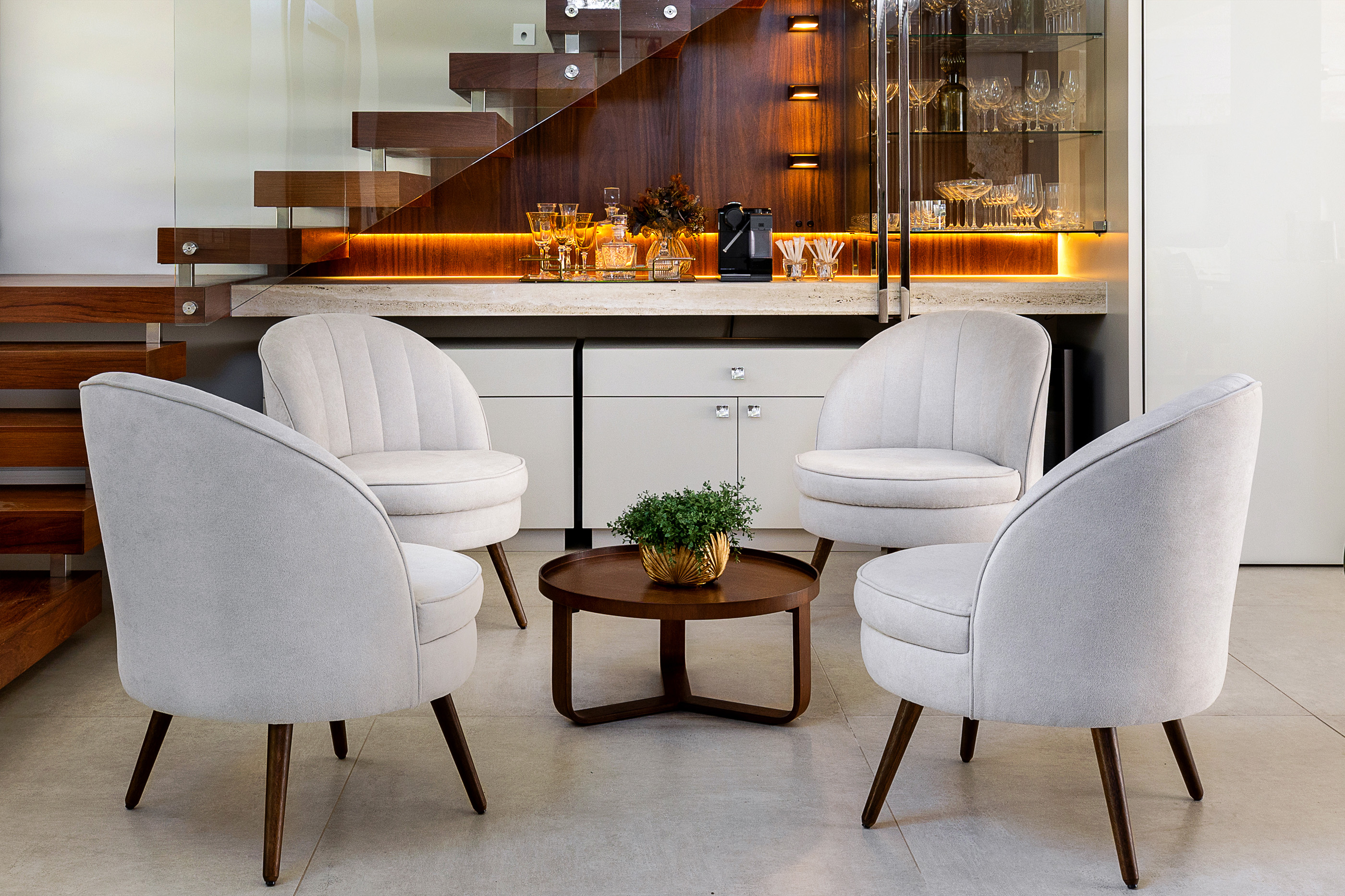 Sala íntima com poltronas claras e bar sob a escada, projeto Repouso